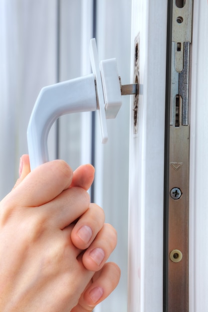 Hands locksmith  remove handle of window frame, close-up.