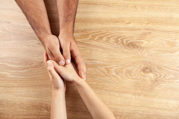 Hands of lovers on the table. view from above