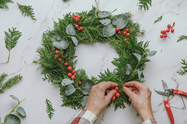 Hands making Christmas wreath DIY Xmas home decor