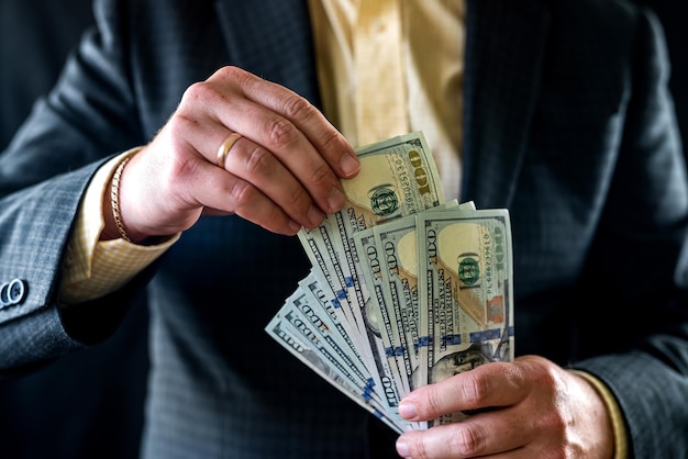 Hands of male boss holding dollar cash and counting them to issue salary