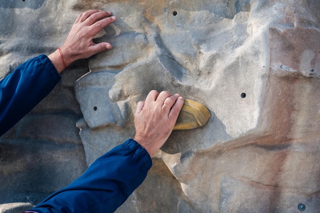 Hands of male climber training on climbing wall