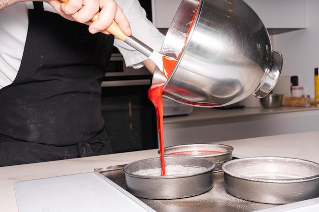 Hands of a man cooking a red velvet cake at home adding the sponge cake in the molds work at home