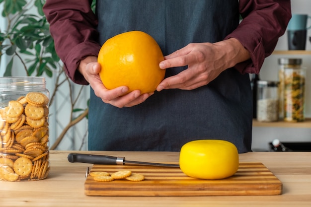 Hands of man hold whole holland cheese Edam and dutch goat cheese from Netherlands on the kitchen