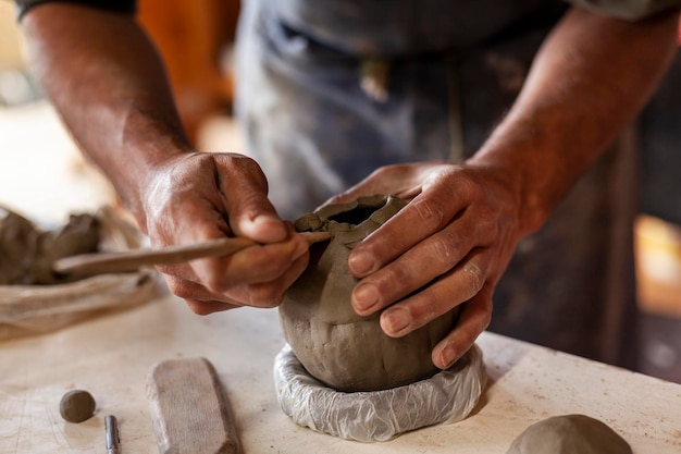 Hands of a man potter making a clay container