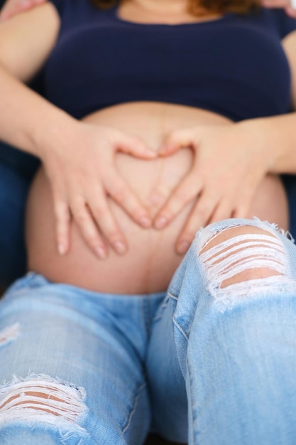 Hands of a man and a woman on a pregnant belly close up Pregnant woman and her husband holding hand together two hands holding baby inside a pregnant woman