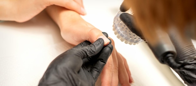 Hands of the manicure master removing dust from nails with a brush cleaning nails in a nail salon