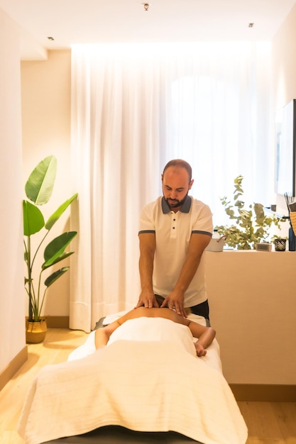 Hands of a masseur performing a massage on the table to a client on the back