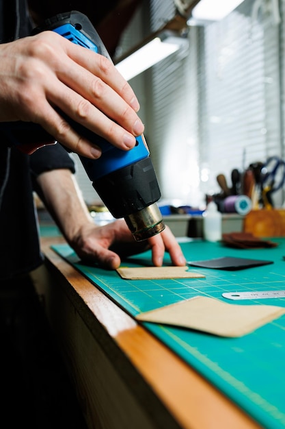 The hands of the master sew handmade leather products Men's hands connect the parts creating quality leather accessories Working process in a leather workshop