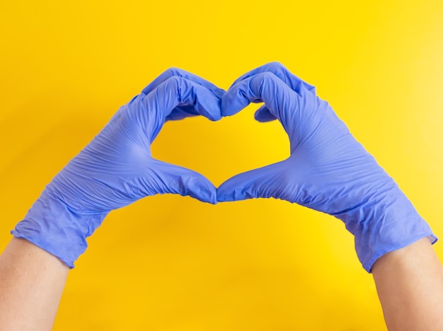 Hands in medical gloves show the heart gesture