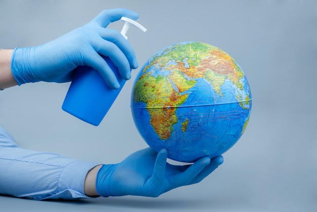 Hands in medical gloves with a globe and a sanitizer. World Coronavirus / Corona virus attack concept.Concept of fight against virus.