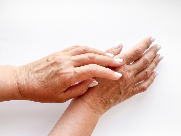 Photo hands middle age woman with white manicured nails gently touching each other on white background top