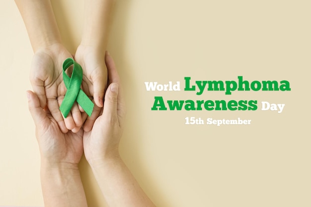 Hands of mother and child hold green ribbon symbol of fight against disease World lymphoma awareness