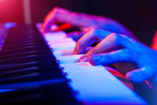 Hands of musician playing keyboard in concert with shallow depth of field