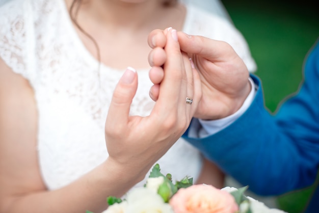 Hands of the newlyweds bride and groom with gold wedding rings