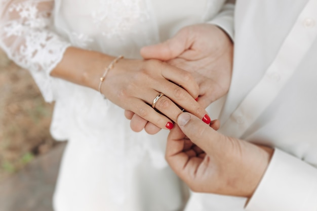 Hands oHands of newlyweds with wedding rings and a wedding bouquet newlyweds