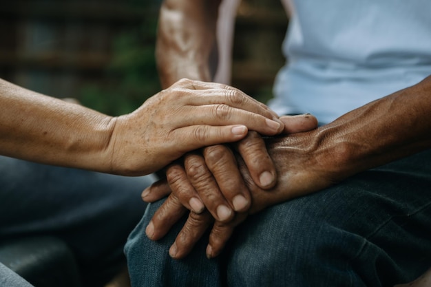 Hands of the old man and a woman hand on the wood table