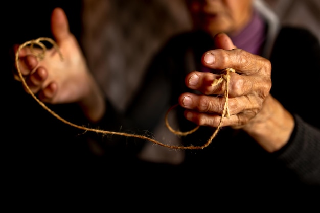 Hands of old woman with polyarthritis disease Canvas strings on fingers of elderly lady puppets