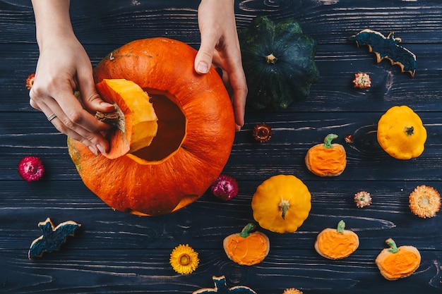 Hands opening Halloween pumpkin on celebrate wooden table Trick or Treat horizontal view from above