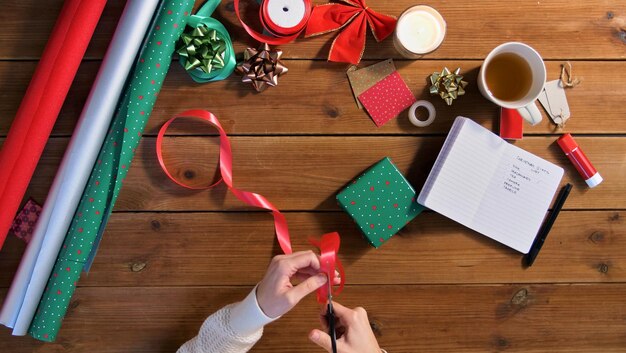 Photo hands packing christmas gift and cutting ribbon