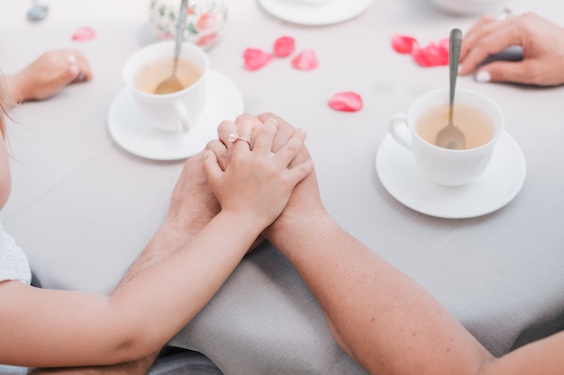 Hands of parents and child on the table holding together.