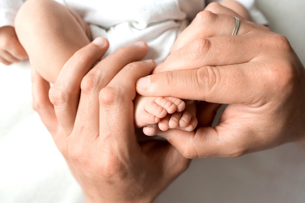 Hands of parents. The legs, feet of the newborn in the hands of mom and dad. High quality photo