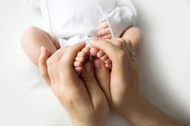 Hands of parents. The legs, feet of the newborn in the hands of mom and dad. High quality photo