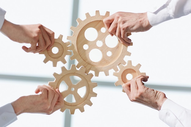 Hands of people office workers business partners making common picture of wooden gears on table