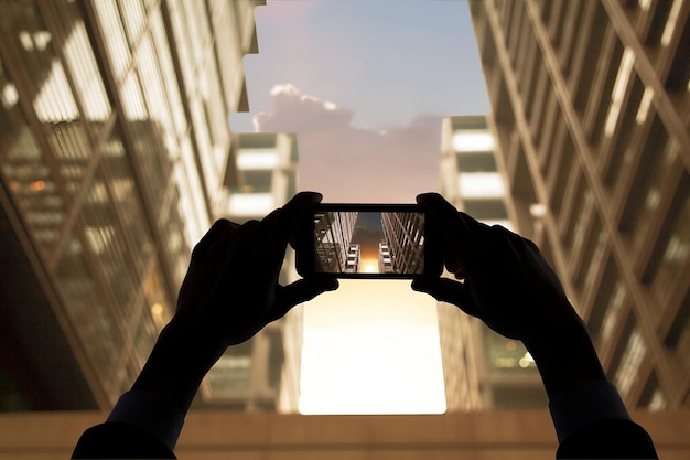 Photo hands photographing skyscraper buildings at sunset