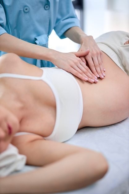 Hands of physiotherapist and osteopath giving professional massage to mom-to-be