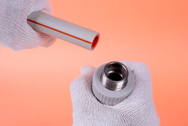 Hands of a plumber hold a plastic pipe on an orange background fixing and installation of plumbingxA