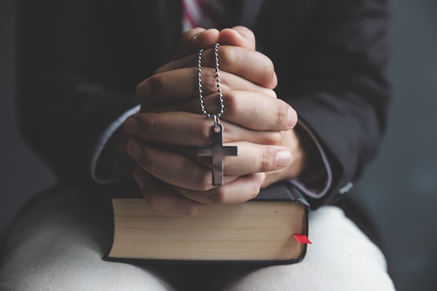 Hands of praying young man and Bible desk 