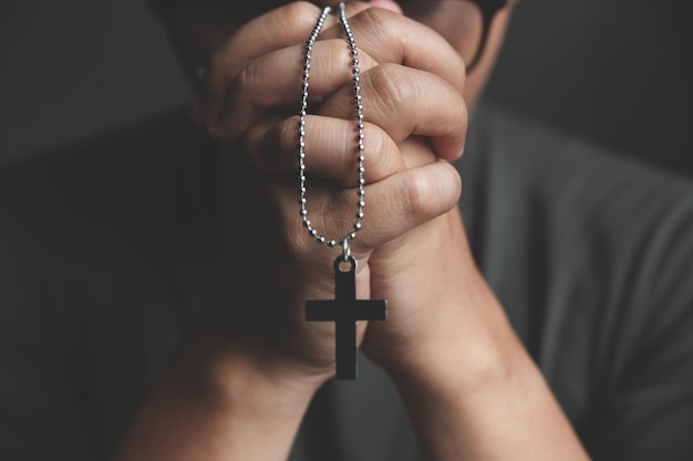 Hands of praying young man on desk 