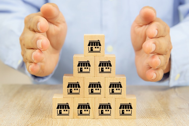 Hands protect wooden blocks Stacked with the franchise marketing icon.