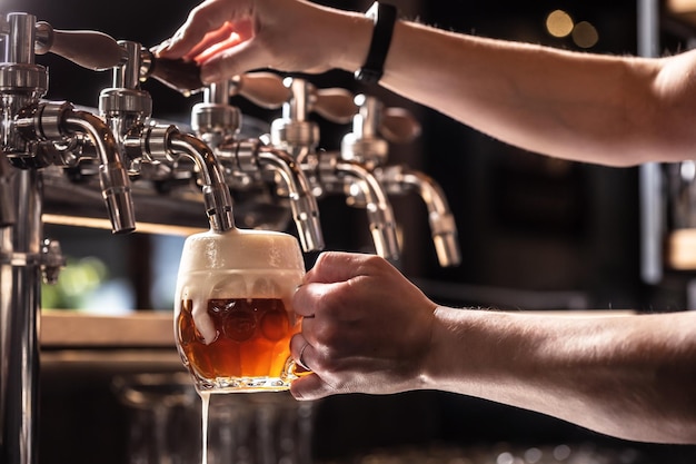 Hands of the pub employee tapping beer into a rounded mug