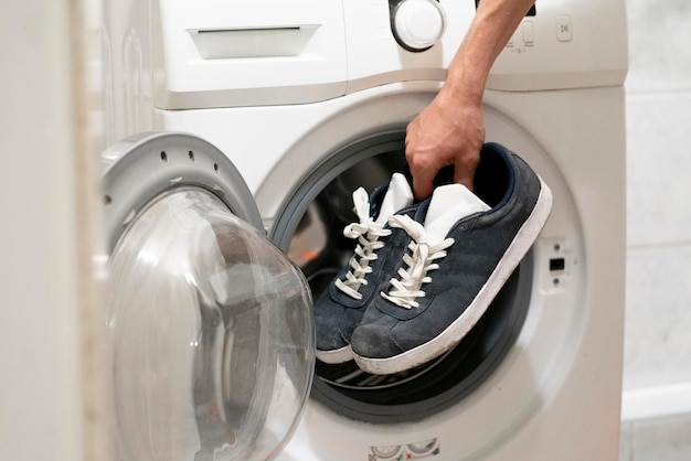 Hands put the dirty sneakers shoes in the washing machine