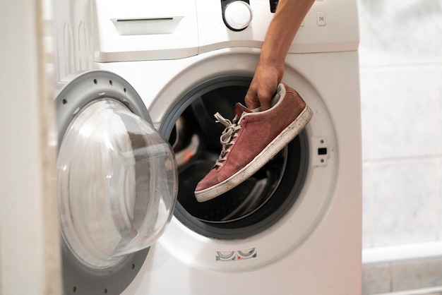 Hands put the dirty sneakers shoes in the washing machine