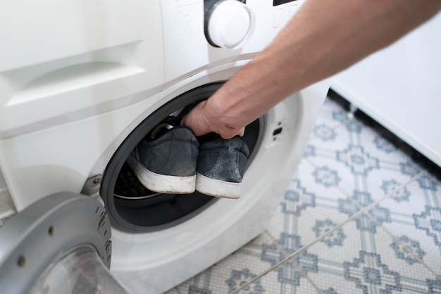 Hands put the dirty sneakers shoes in the washing machine