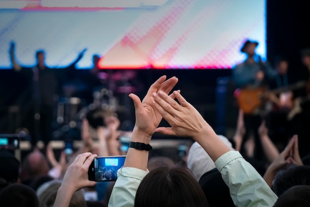 Hands raised up at big open air concert with the crowd background girl parodies a musical group at a street concert