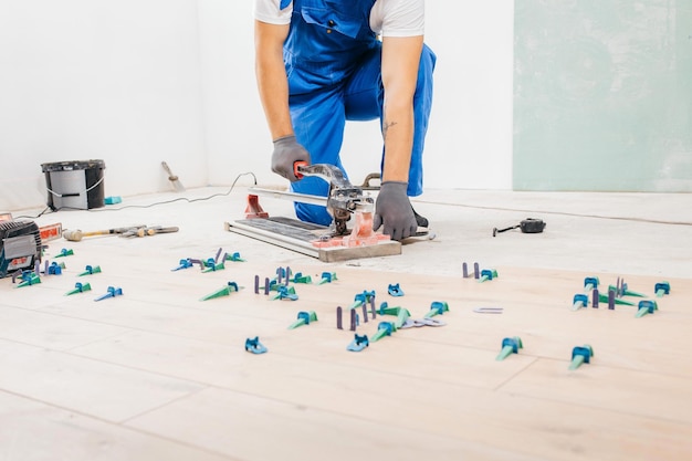 Hands of repairman cut ceramic tiles at tile cutter on the floor. Close up