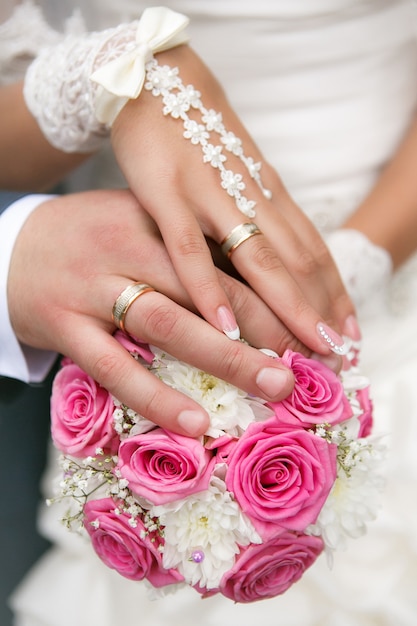 Hands and rings on wedding bouquet