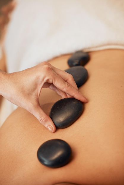 Hands rock and spa for back massage in relax for healthy wellness zen or physical therapy treatment at resort Hand of therapist applying rocks in relaxation stress relief and luxury care for skin