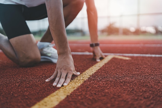 Hands runner ready start to run athlete sportman training run on lane at the stadium in morning Runner man wearing white vest to practice running prepare for competition race