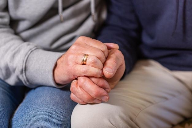 Hands of senior couple holding together care and support