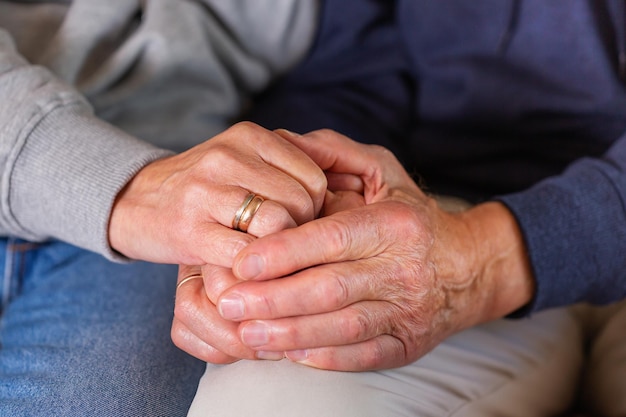 Hands of senior couple holding together care and support