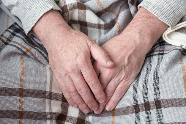 Hands of a senior man on a blanket, concept of caring for old people