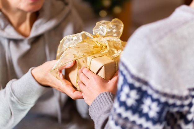 Hands of senior woman and a child holding Christmas gift