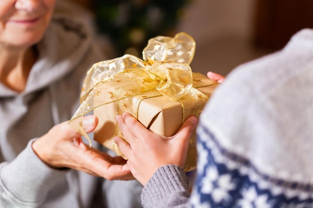 Hands of senior woman and a child holding Christmas gift