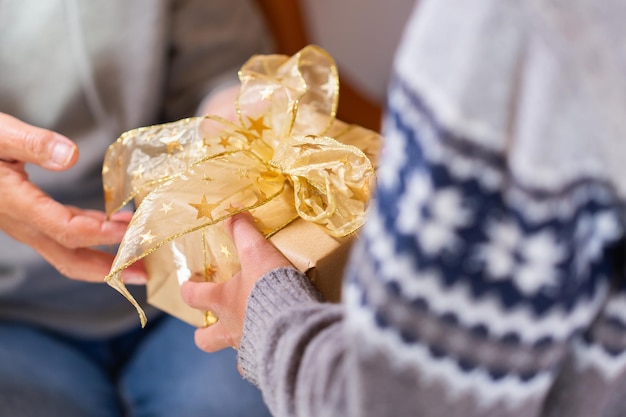 Hands of senior woman and a child holding Christmas gift