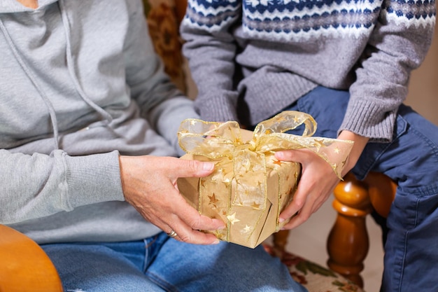 Hands of senior woman and a child holding Christmas gift