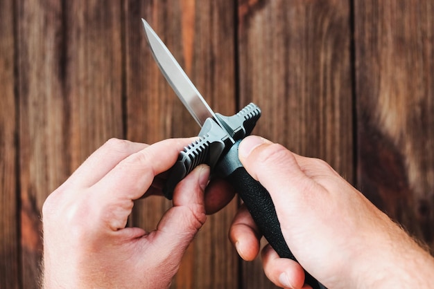 Photo hands sharpening a knife on a wooden background